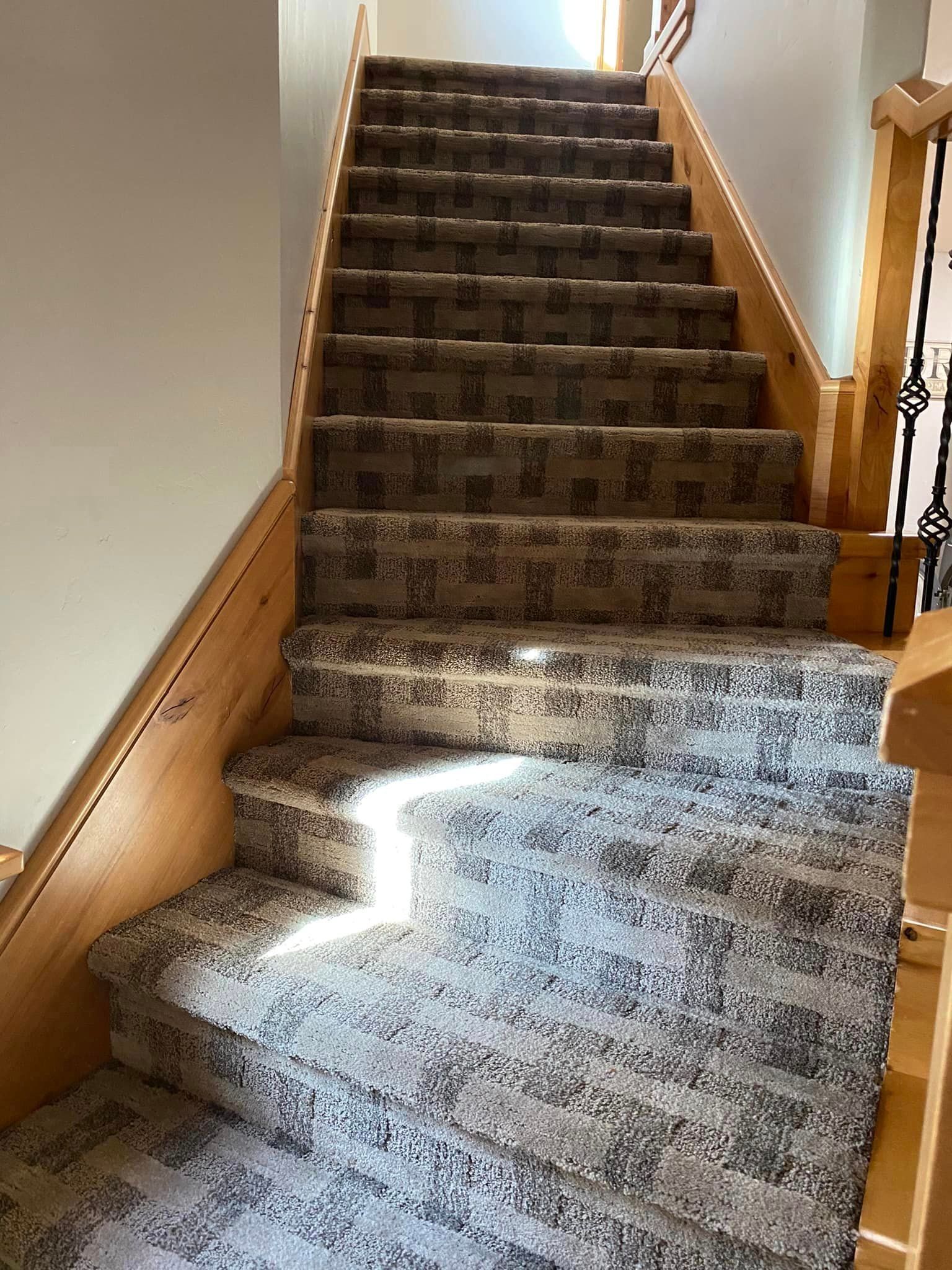 A staircase with a carpeted staircase and a wooden railing.