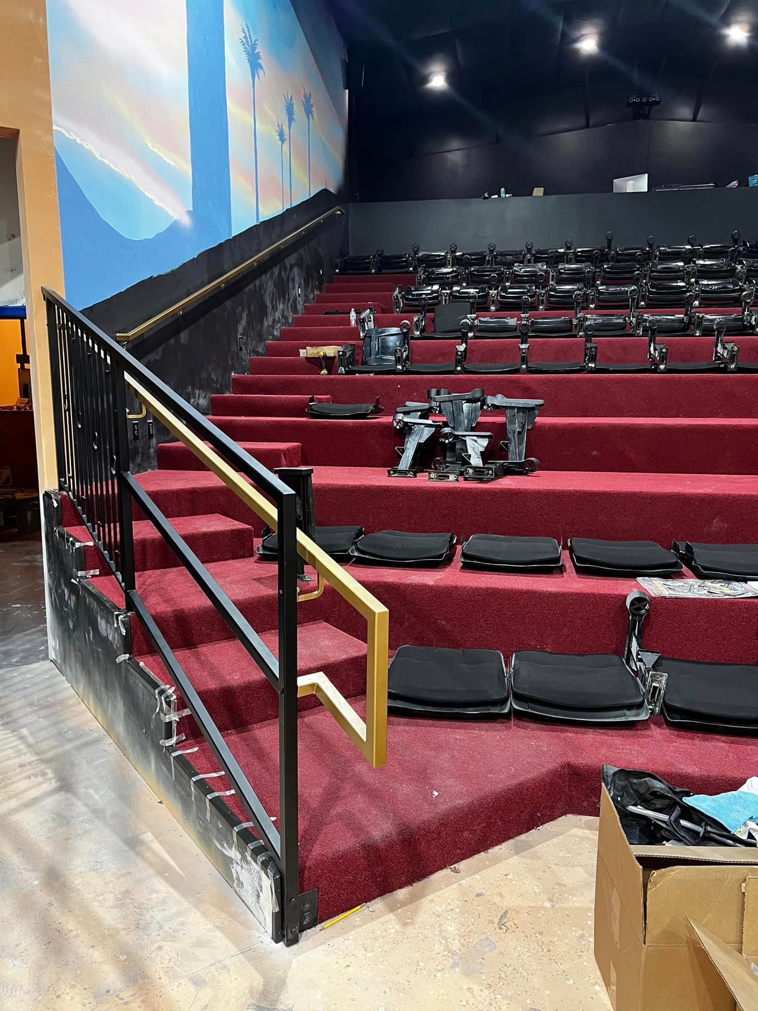 An empty auditorium with red seats and a black railing.