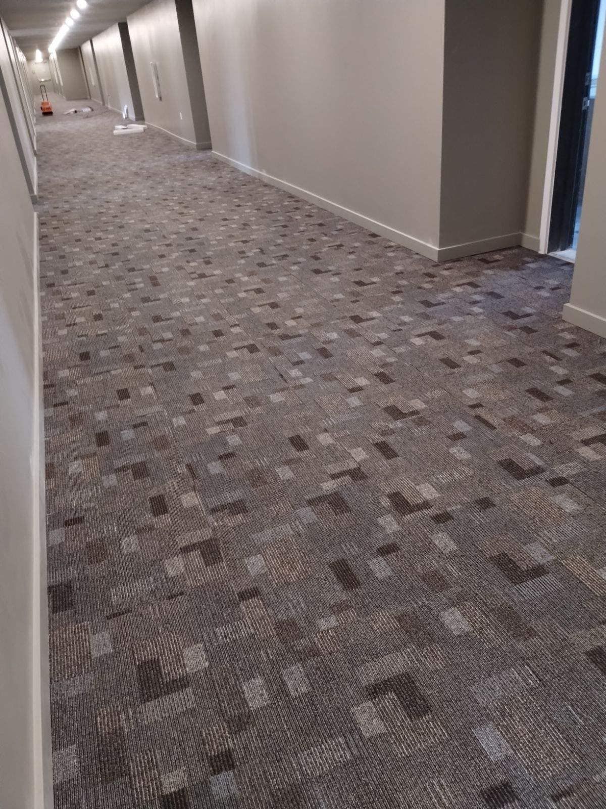 A long hallway with a carpeted floor in a building.