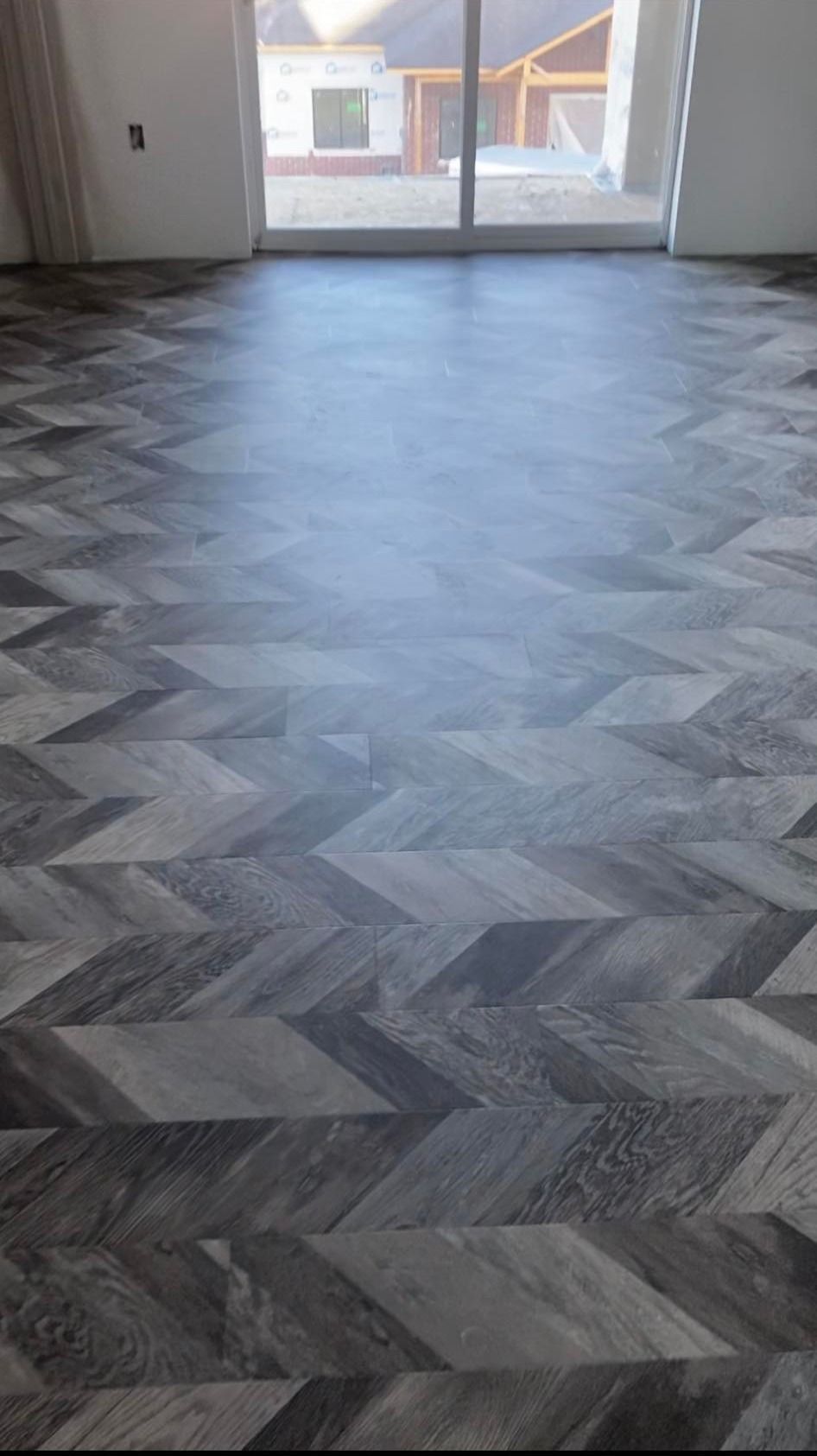 A room with a herringbone floor and a sliding glass door.