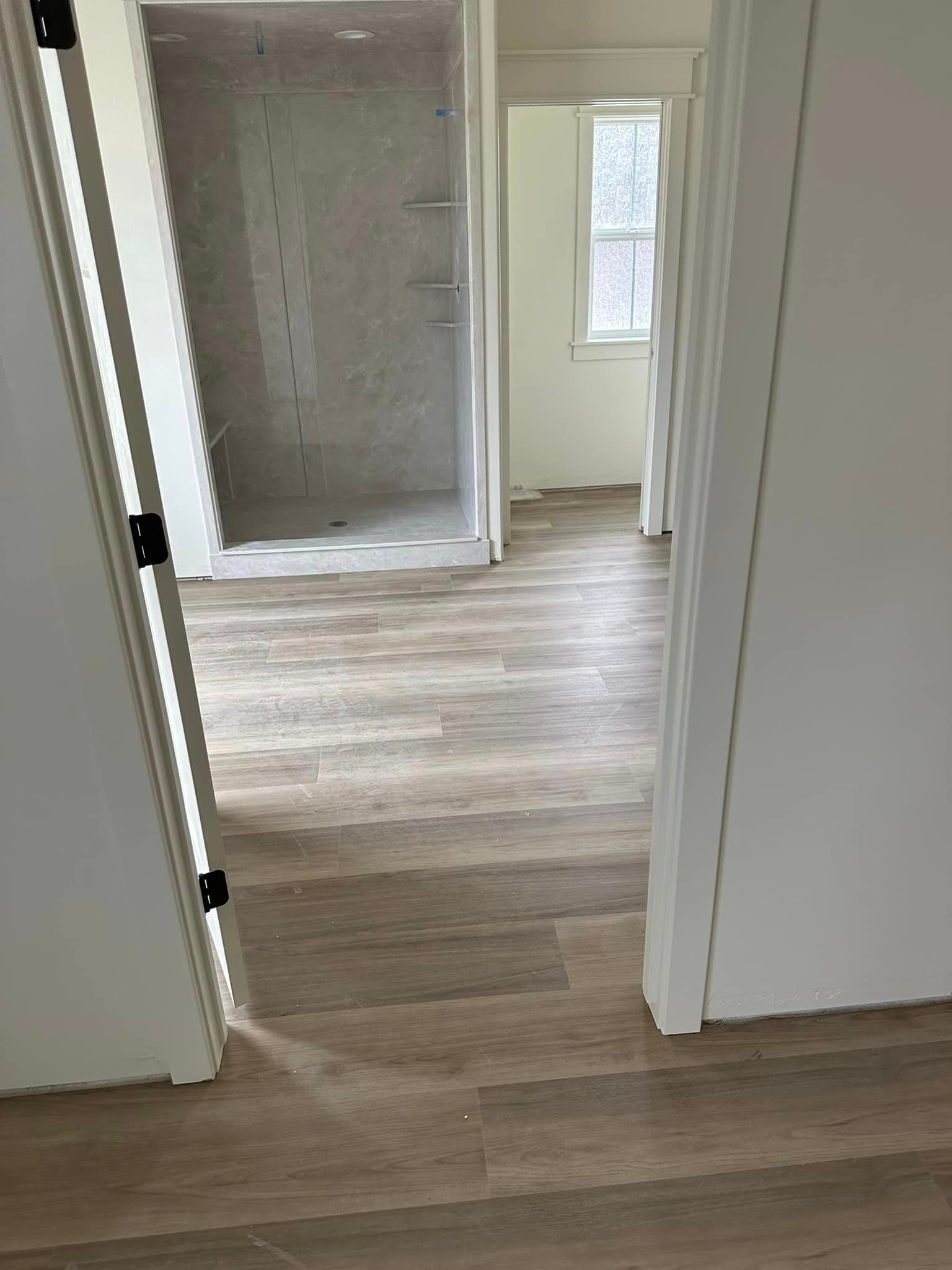 A room with hardwood floors and a walk in shower.