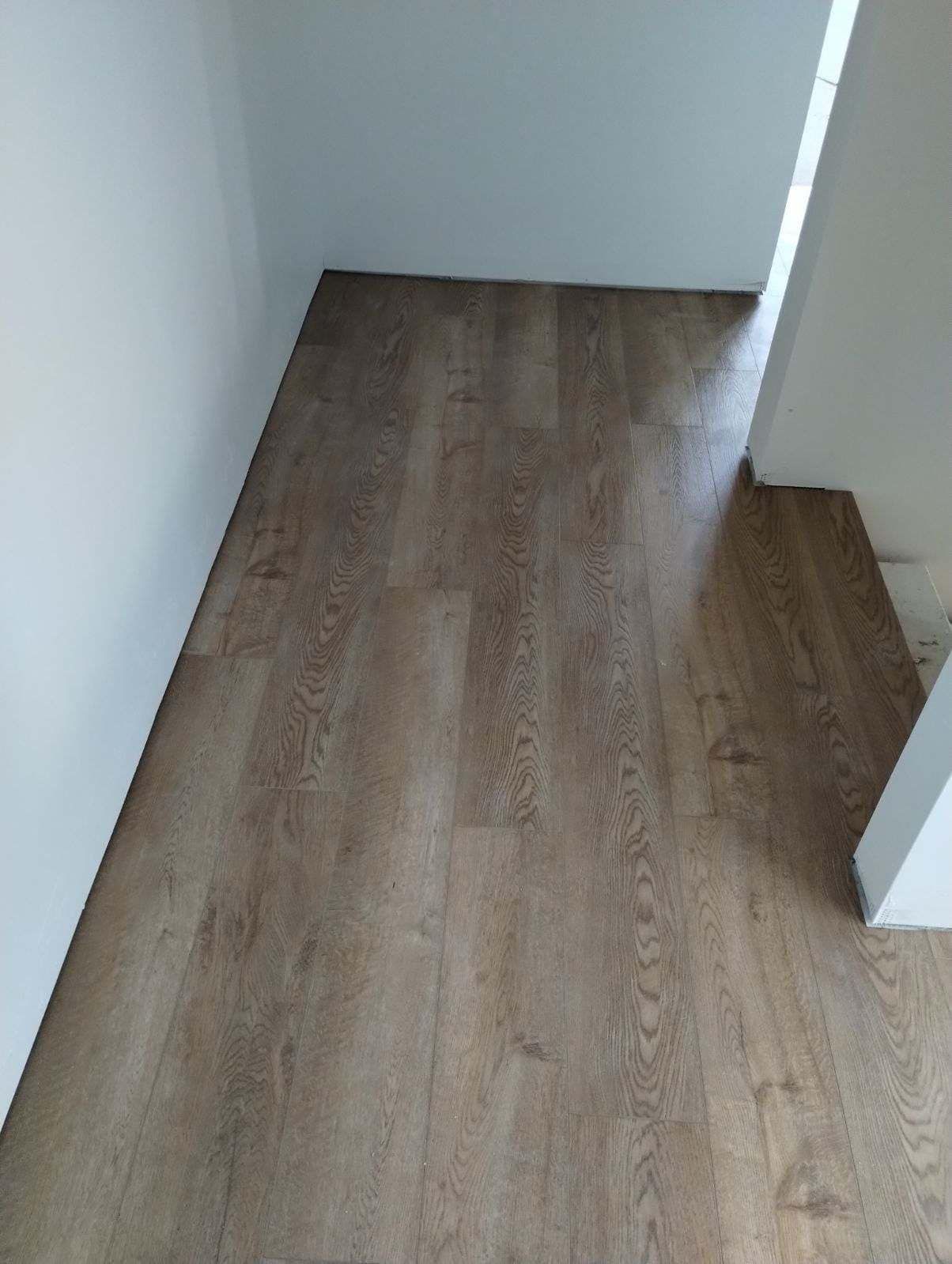 A room with a wooden floor and a white wall.