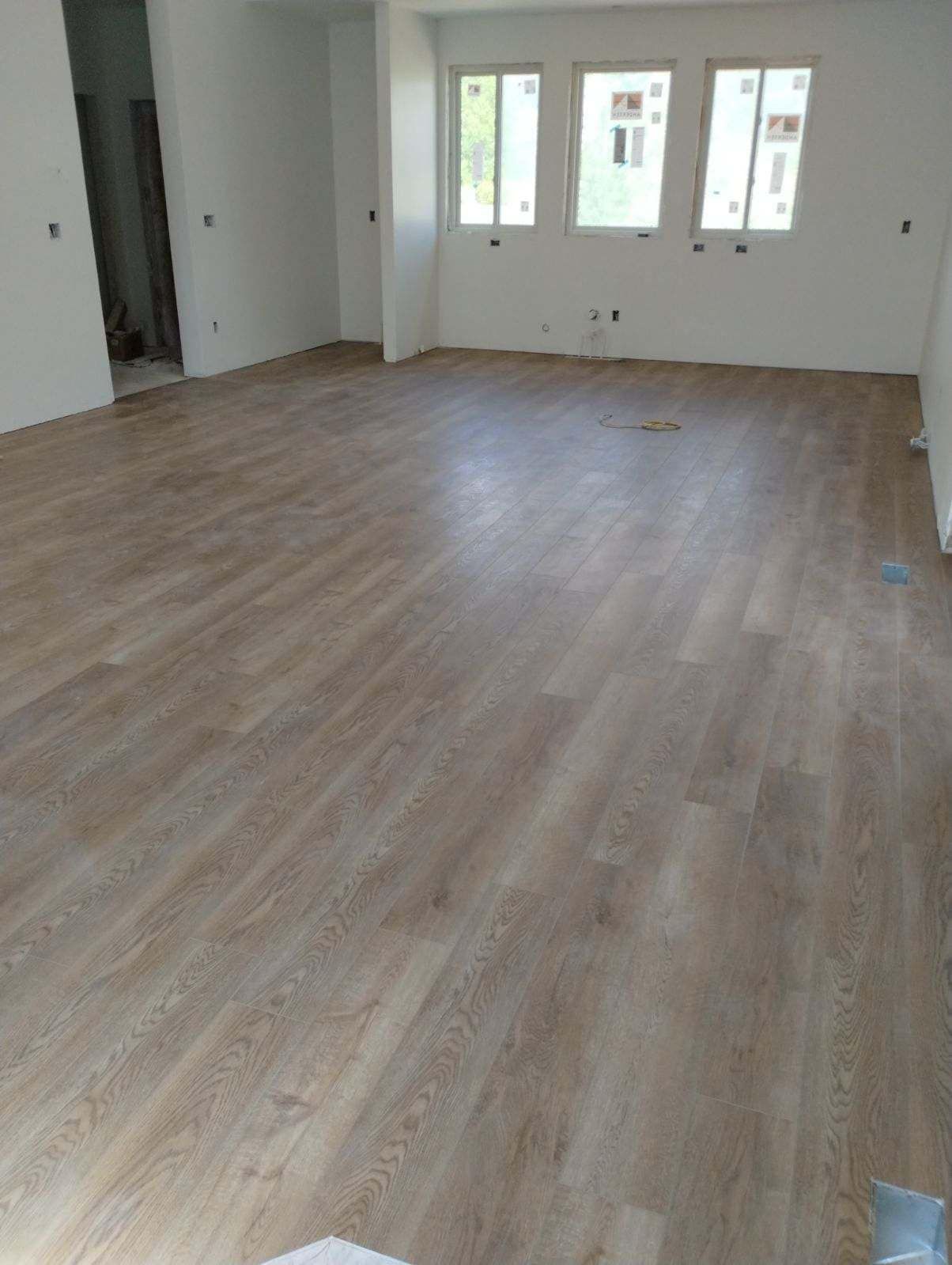 A large empty room with a wooden floor and white walls.