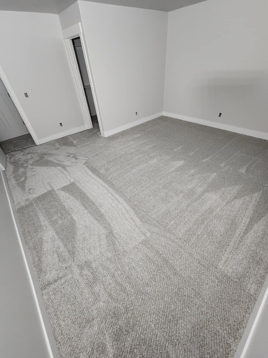 A bedroom with a large carpeted floor and white walls.