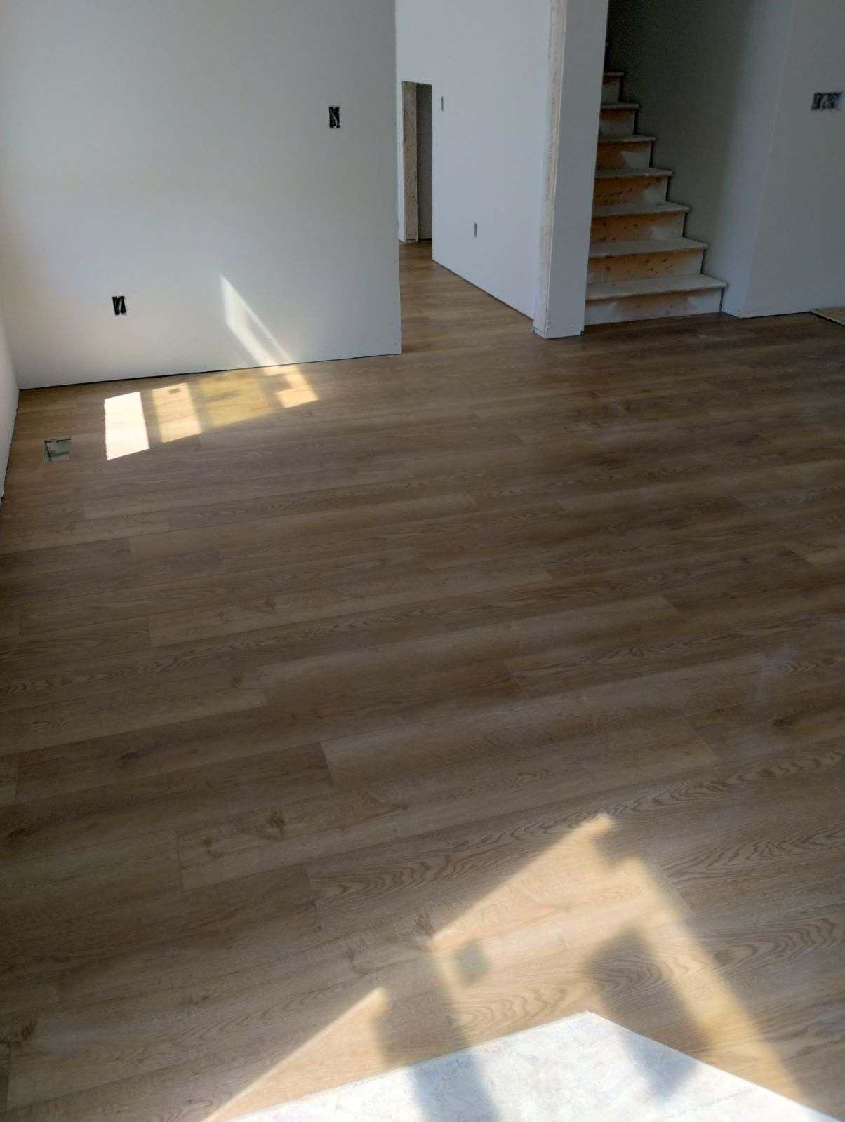 A living room with a wooden floor and stairs.