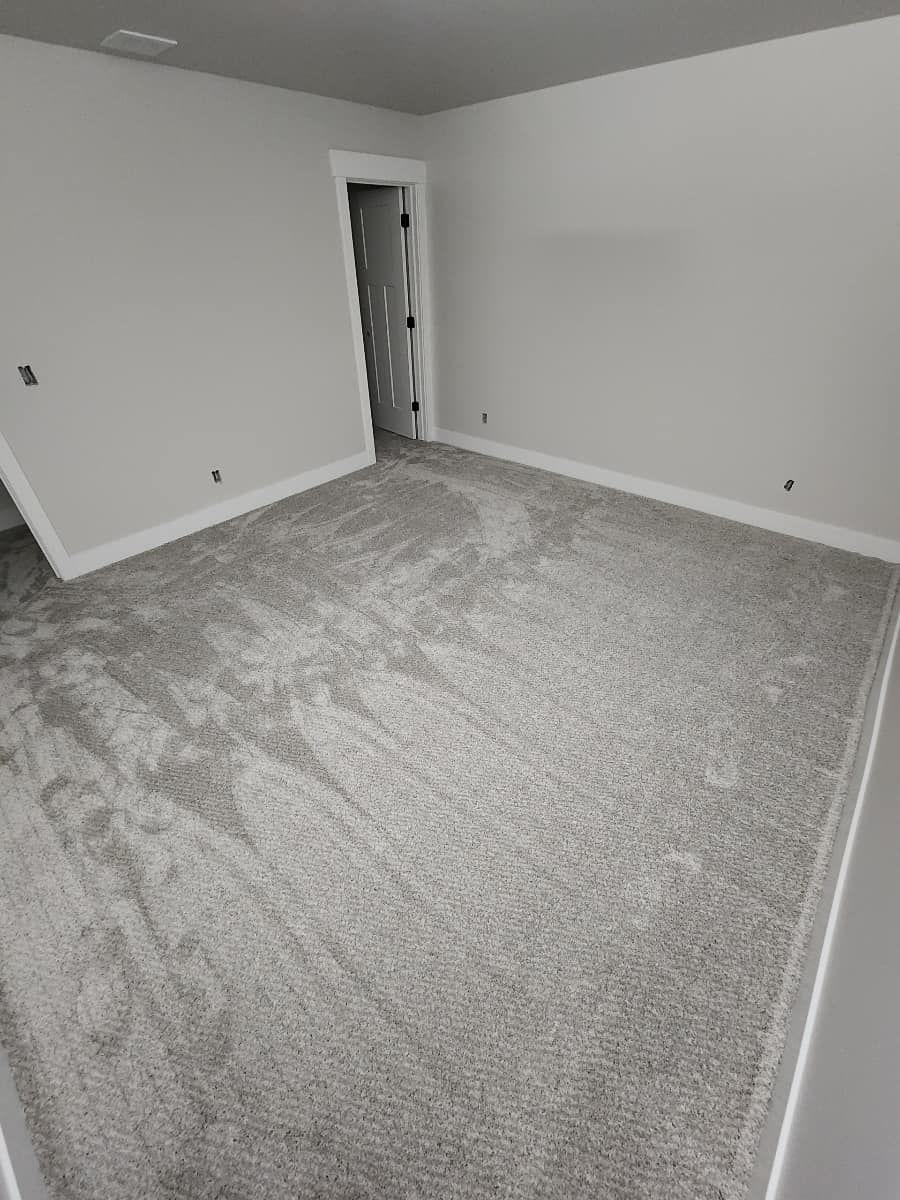 A bedroom with a large carpeted floor and white walls.