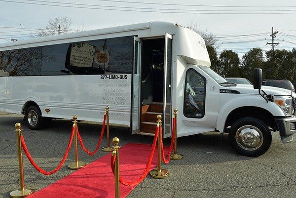 a white bus is parked next to a red carpet .