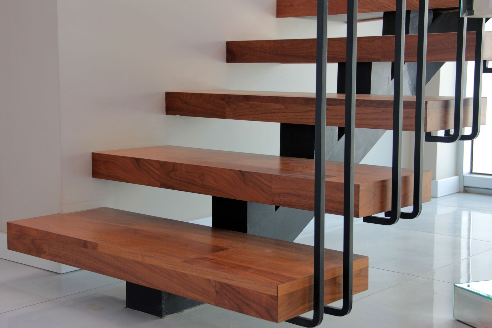 Wooden floating staircase with black metal railing.
