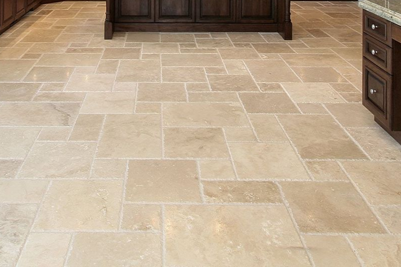 Beige travertine tile kitchen floor with dark brown cabinets.