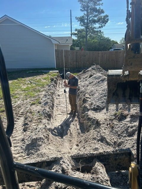 A man is digging a hole in the dirt in front of a house