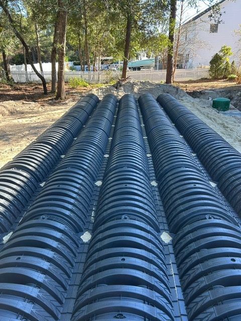 A row of black pipes sitting on top of a dirt field.