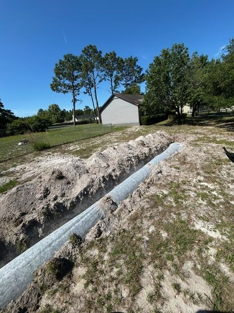A pipe is laying in the dirt in front of a house