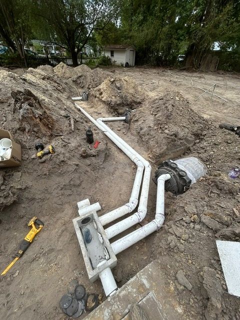 A bunch of pipes are laying in the dirt.
