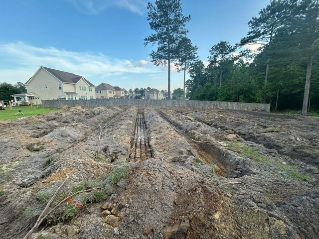A large dirt field with a house in the background.