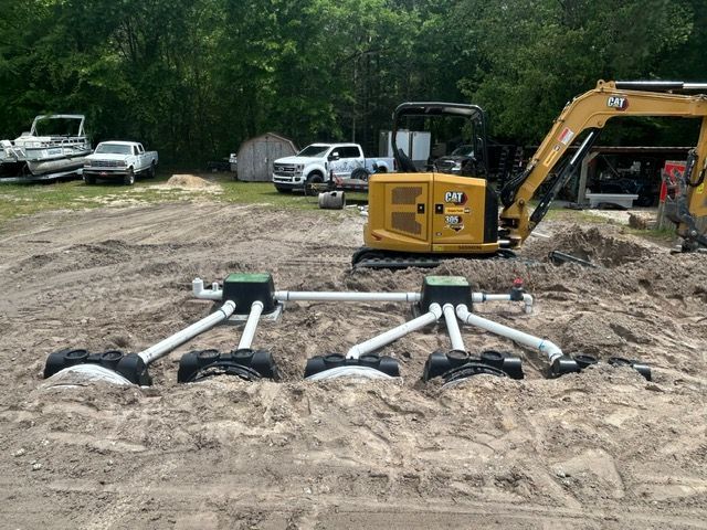 A yellow excavator is sitting in the middle of a dirt field.