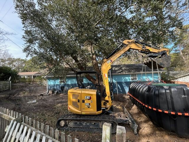A yellow excavator is digging a hole in the dirt in front of a house.