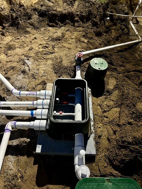 A bunch of pipes are connected to a box in the dirt.