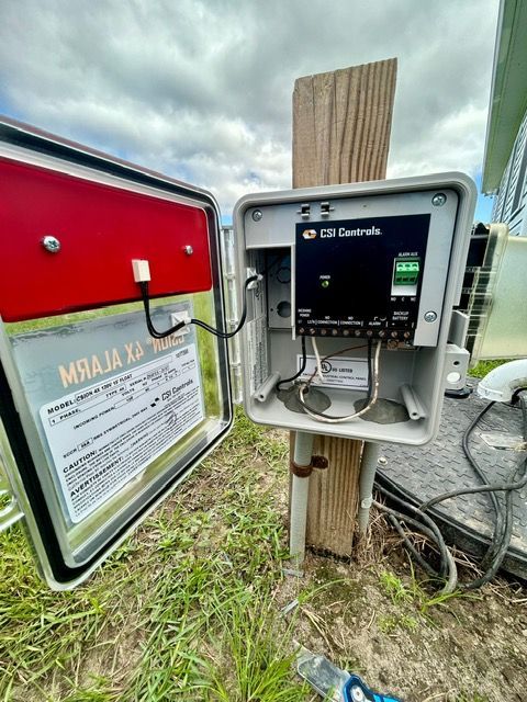 A box is sitting on top of a wooden post in the grass.