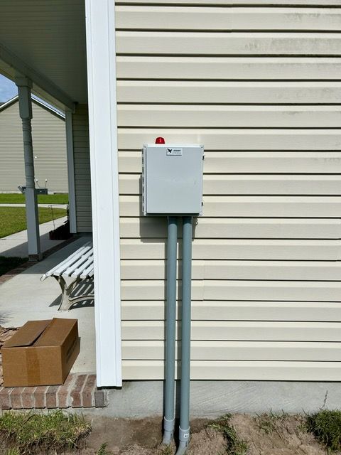 A box on the side of a house with a red light on it.