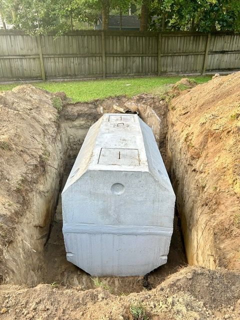 A large concrete septic tank is sitting in a hole in the ground.