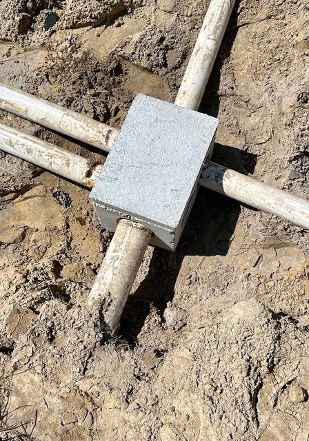 A box is sitting on top of a pile of dirt next to pipes.