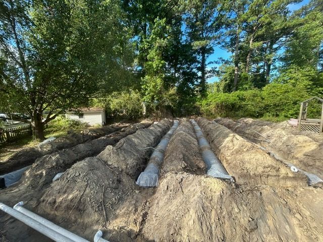 A pile of dirt with pipes in it and trees in the background.