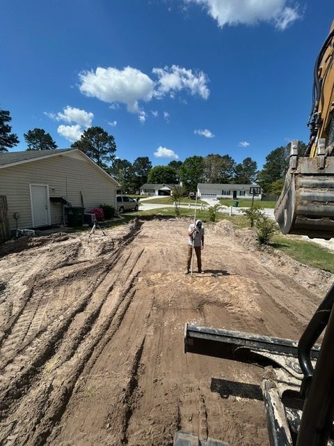 A man is standing on a dirt road next to a bulldozer.