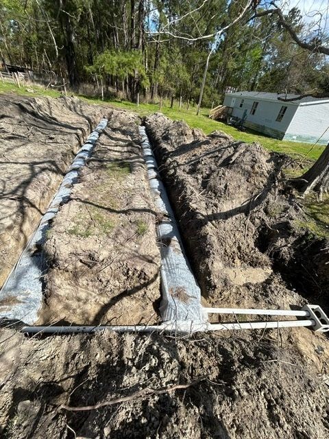 A drainage system is being installed in a dirt field.