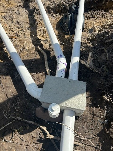 A bunch of white pipes are laying in the dirt.