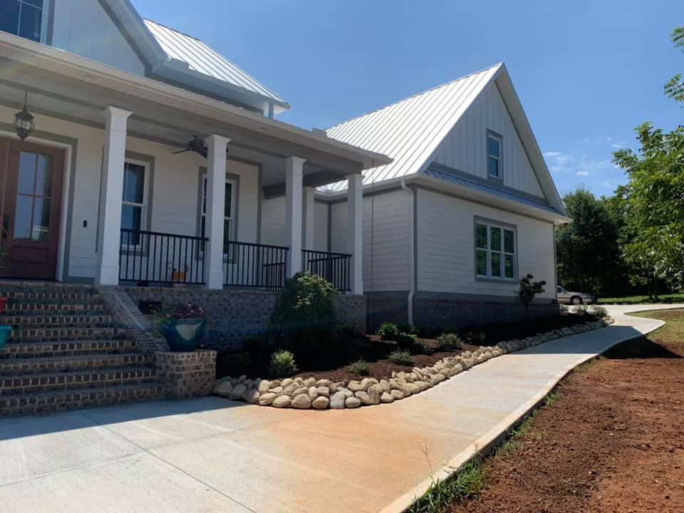 A white house with a porch and a walkway leading to it.
