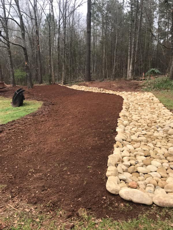 A path made of rocks and mulch in the middle of a forest.
