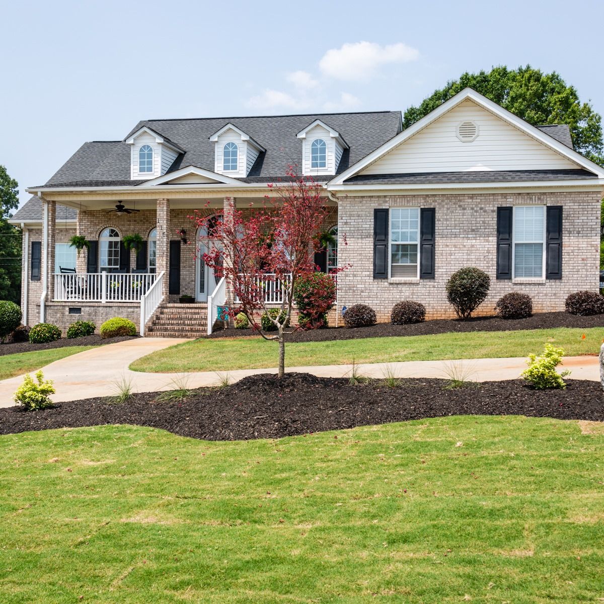 A large brick house with a large lawn in front of it