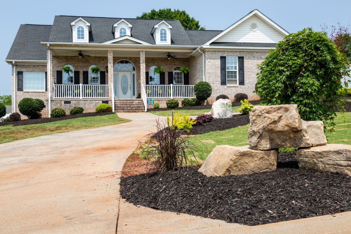 A large brick house with a large driveway and a large porch.
