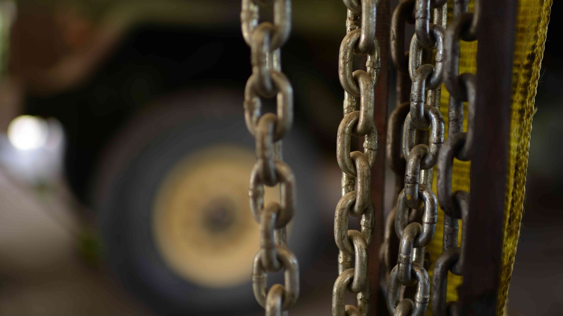 Rusty metal chains hanging in front of a blurred vehicle wheel