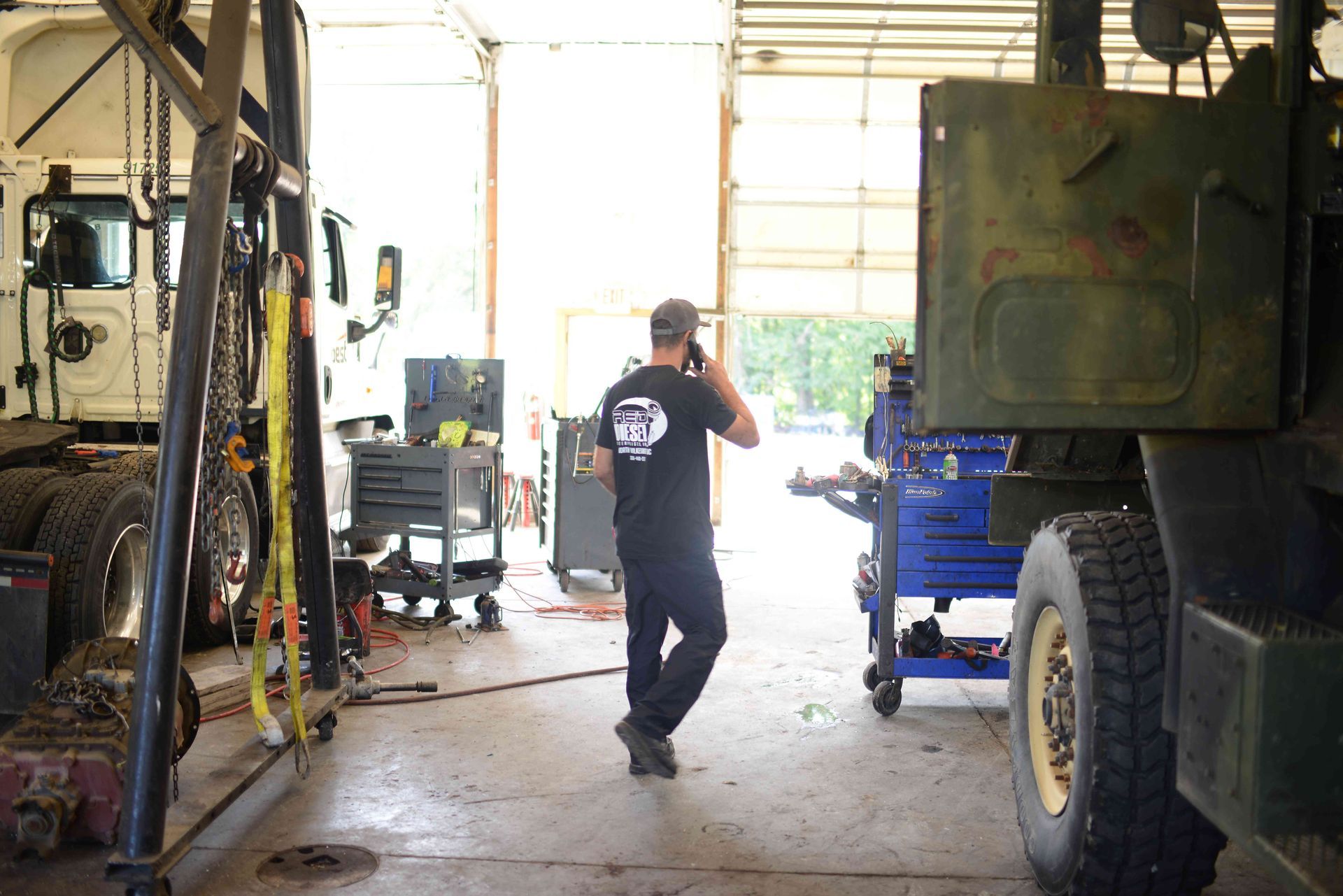 Person walking through a vehicle repair garage between large trucks and equipment