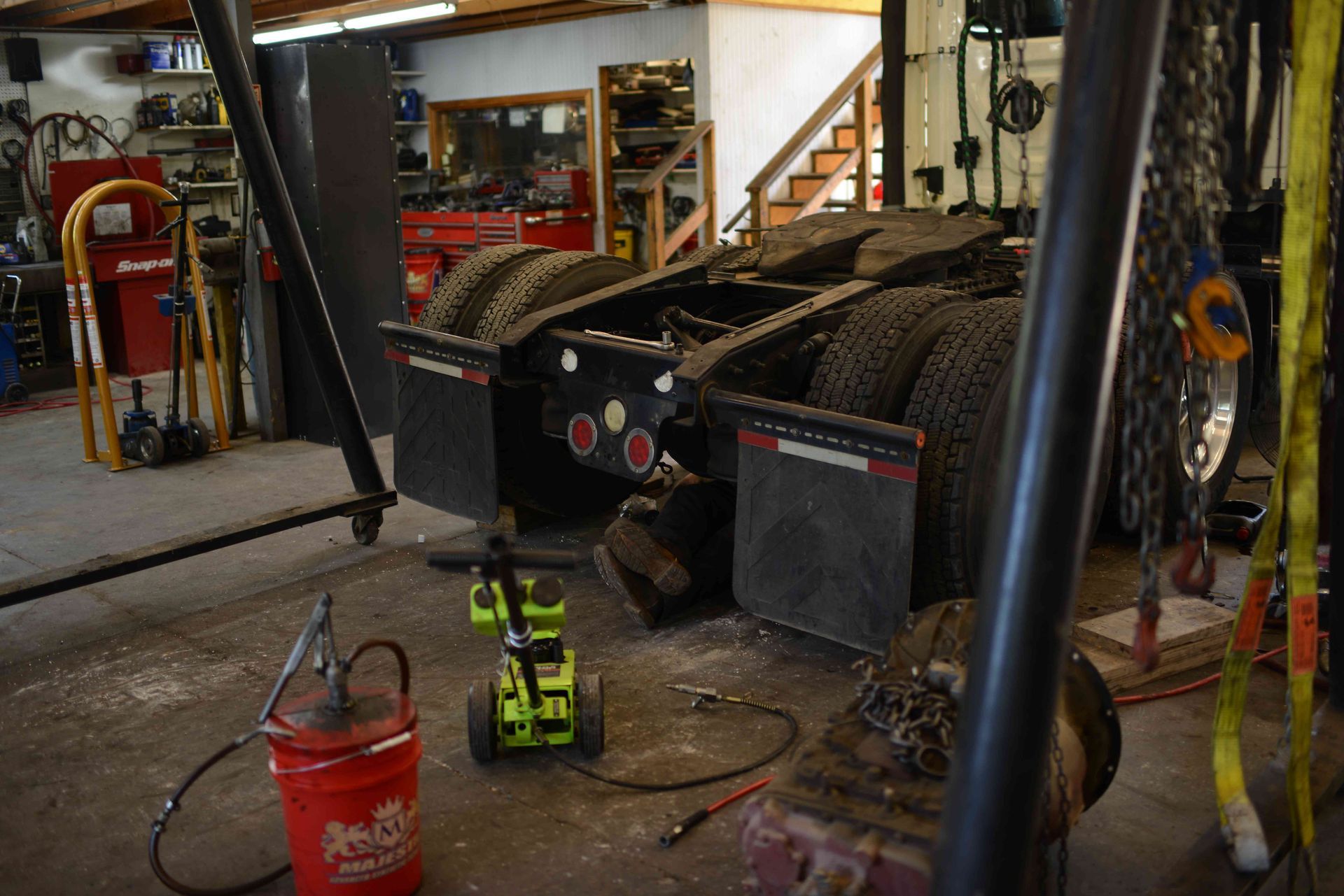 Workshop with a large tracked machine, a red bucket, and a small green toy vehicle on the floor.