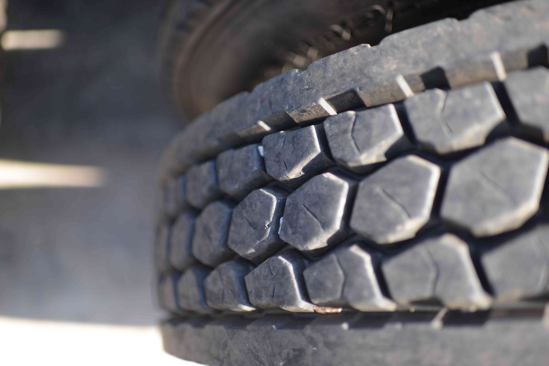 Close-up of a truck tire with a worn tread pattern on the road.