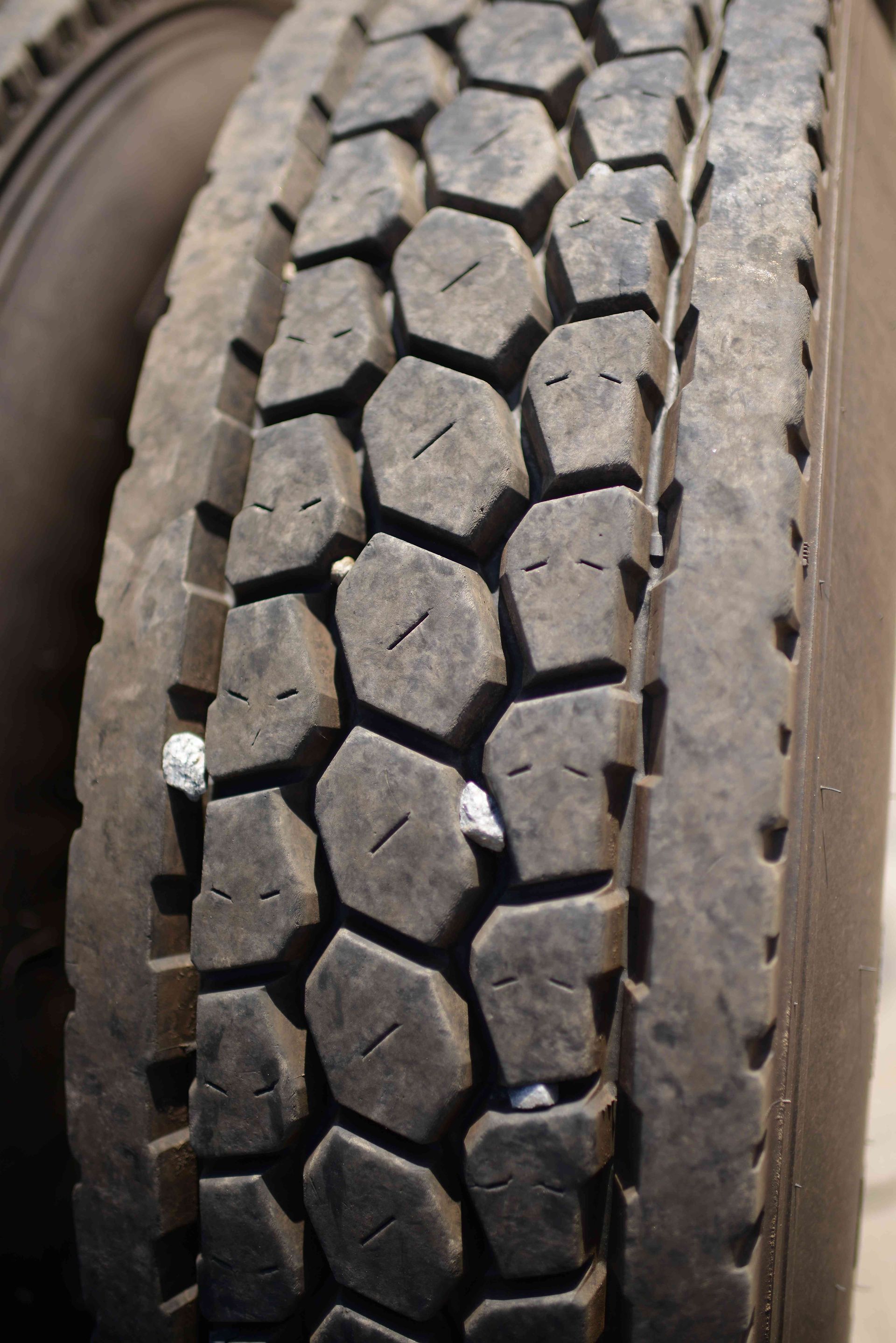 Close-up of a worn truck tire tread with dirt and sidewall visible