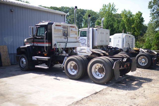 White semi-truck chassis parked beside a gray building in an industrial yard