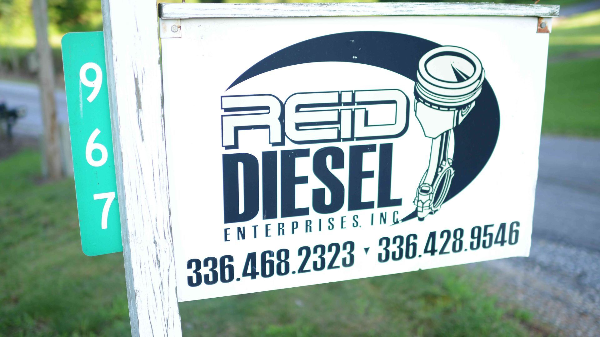 REID Diesel Enterprises sign on white truck-side panel with phone number and piston logo