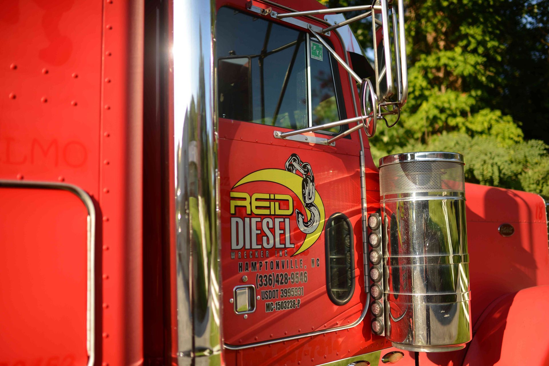 Close-up of a red semi truck cab with chrome grille and 