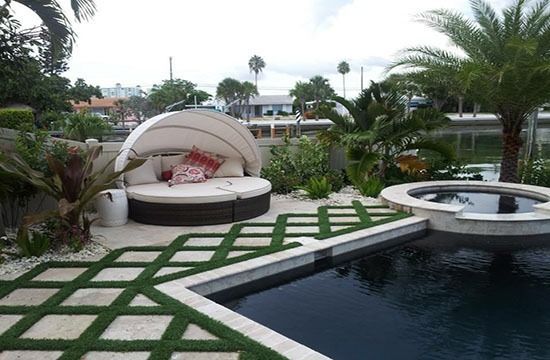 Luxury patio with white canopy lounge, patterned stone walkway, and a pool in a tropical garden
