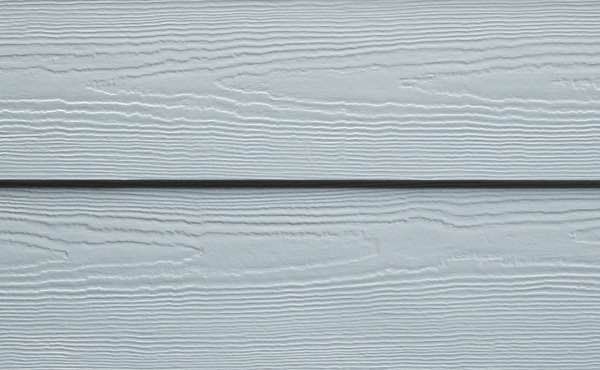 Blue-gray wood siding with visible grain texture, horizontally aligned, with a shadow line between planks.