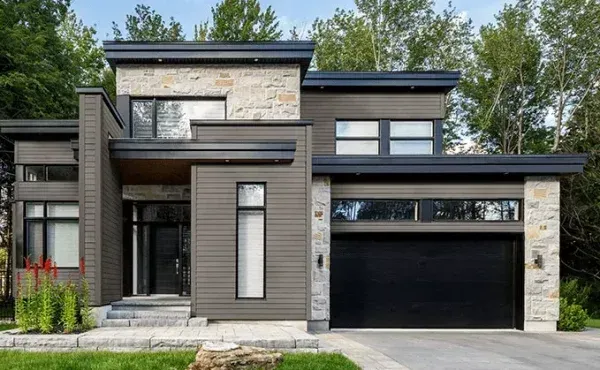 Modern two-story home with stone and gray siding, black garage door, and manicured lawn.