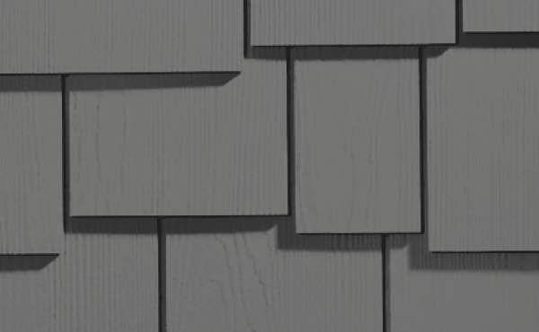 Gray, overlapping rectangular shingles on a wall, arranged in a staggered pattern.