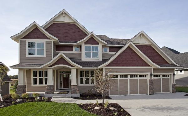 Two-story house with brown siding, brick red accents, and a three-car garage.