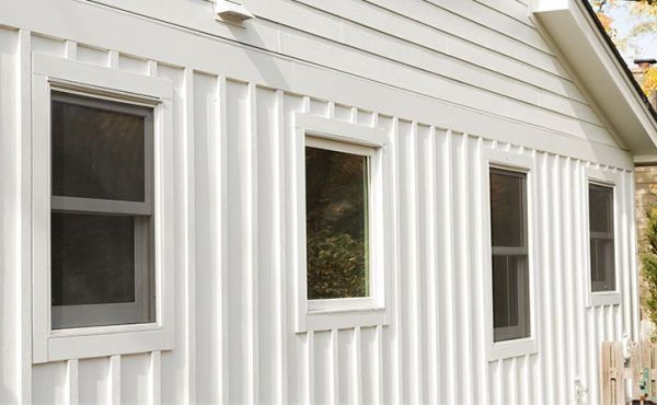White building exterior with vertical siding and four rectangular windows.