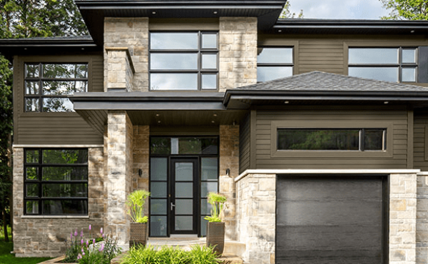 Modern two-story house with stone facade, dark trim, large windows, and a garage door.