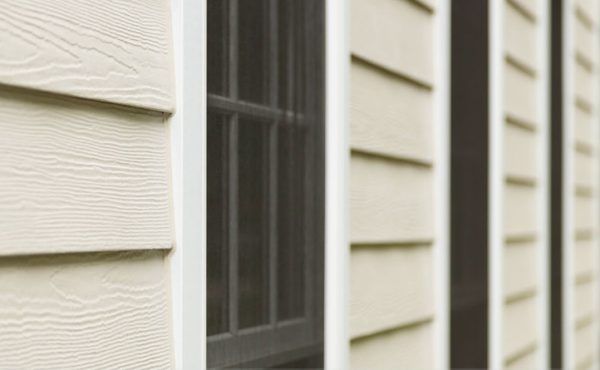 Beige clapboard siding next to a window with dark frame, set outside.