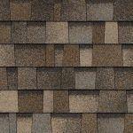 Brown and tan asphalt roof shingles, textured, layered pattern.